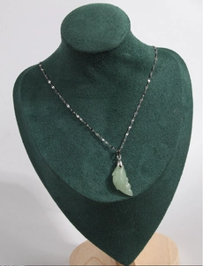 Détail d'un pendentif poisson en jade vert sur chaîne argentée sur buste en velours