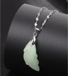 Vue détaillée du pendentif poisson en jade vert clair sur une chaîne en argent poli