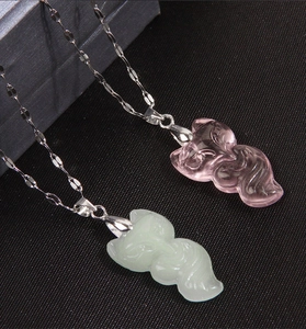 Detalle de collares con colgante de zorro en cristal rosa y textura de jade verde