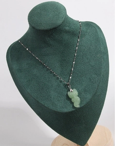 Detalle del collar con colgante de zorro de jade verde claro en un busto de exhibición
