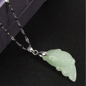 Collier avec pendentif poisson en jade vert et chaîne argentée sur fond noir