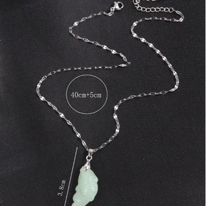 Collier en argent avec un pendentif en jade vert clair de 3,8 cm sur un fond texturé