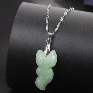 Collar de jade con dije de zorro y cadena plateada en soporte de exhibición negro
