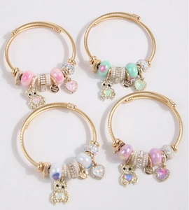 Detailed view of four beaded bracelets with gold bear and heart charms in soft pastel colors