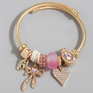 Dettaglio del bracciale dorato con ciondoli a cuore rosa, fiocco e incisione LOVE