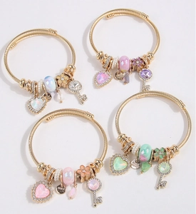 Detail of gold spiral bracelets featuring heart gems, key charms and floral pendants