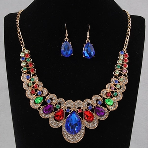 Luxurious gold jewelry set with colorful gemstones and large blue pendant on a model