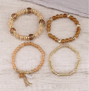 Detail of four-piece Bohemian beaded bracelet set with golden charms and tassels