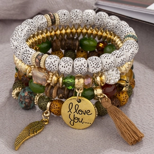 Detail of bohemian layered beaded bracelets with gold wing charm and brown tassel