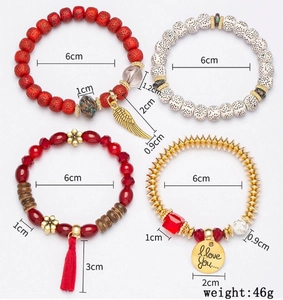 Detail of 4-piece Bohemian beaded bracelet set with red tassels and gold wing charms