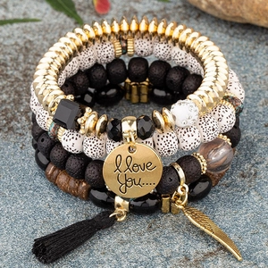Detail of bohemian multilayer beaded bracelet set with gold feather and tassel charms