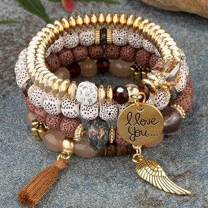 Detail of bohemian stackable beaded bracelets with wing charm, tassel and engraved coin