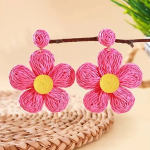 Bohemian style pink and yellow raffia flower earrings hanging on a natural branch