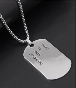 Macro shot of polished silver shield dog tag pendant with box chain and custom engravings