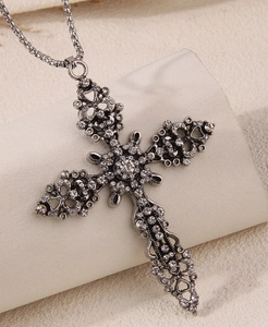 Close-up of vintage silver cross necklace with sparkling crystals and hollow heart details