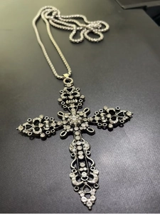 Detail of gothic silver cross necklace with sparkling white rhinestones and thick chain