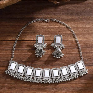 Detailed view of vintage silver jewelry set with square white stones and hanging bells