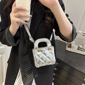Silver quilted mini bag with gold hardware and top handle shown in a fashion outfit