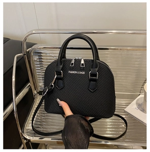 Detailed view of black textured shell bag featuring silver hardware and top zippers