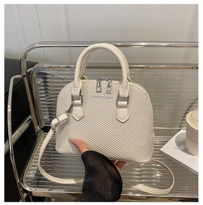 Close-up of beige woven texture handbag with silver zippers and fashion lettering detail
