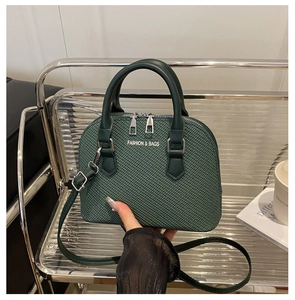 Detail of dark green woven texture handbag with silver lettering and adjustable strap
