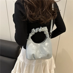 Light blue pleated cloud crossbody bag with fashion and bags text in a minimalist setting