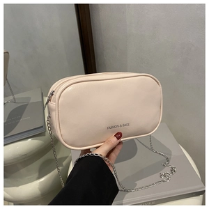 Detail of a beige chain crossbody bag with FASHION & BAGS logo held by a model
