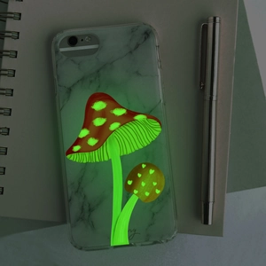 Luminous mushroom phone case with marble pattern glowing in the dark on a notebook