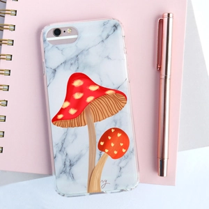 Detailed view of marble pattern phone case with mushroom illustration on pink notebook