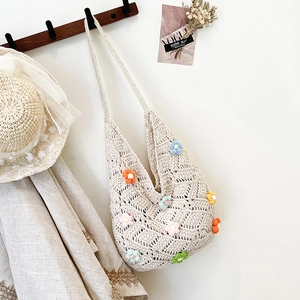 Sac hobo au crochet blanc cassé avec fleurs colorées suspendu à un support en bois