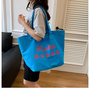 Detail of blue canvas tote bag showing its large capacity and white script lettering
