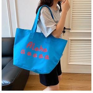 Close-up of bright blue canvas tote bag with red lettering shown in an indoor setting