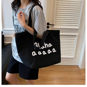 Detail of the black canvas tote bag with white Aloha print and wide shoulder straps