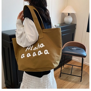Close-up of ginger yellow canvas tote bag with white letter print and large capacity