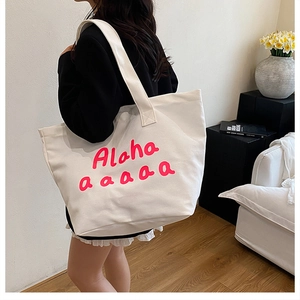 Detailed view of large white canvas tote bag with pink Alaha script and sturdy shoulder strap