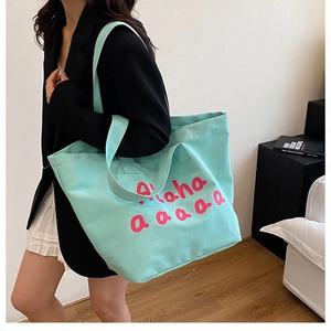 Detail of mint green canvas tote bag featuring pink Aloha lettering and shoulder strap