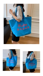 Macro view of blue canvas tote bag with red Aloha lettering print and durable strap