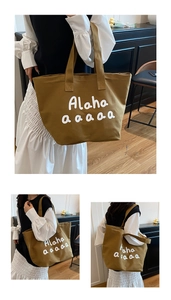 Detail of caramel brown canvas tote bag featuring white artistic font and sturdy handles