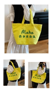 Detailed view of yellow canvas tote bag with green letter print and reinforced stitching
