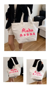 Detail of white canvas tote bag with pink calligraphy lettering and wide shoulder strap