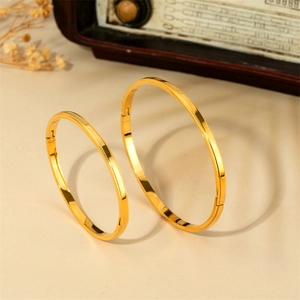 Détail des bracelets en acier titane doré avec motifs dentelés et fermoirs articulés