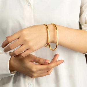 Gros plan de bracelets minimalistes en titane doré avec texture dentelée sur un poignet