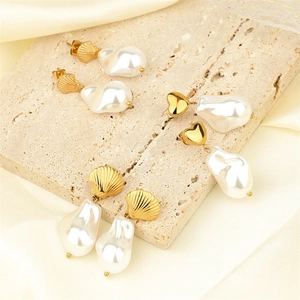 Elegant baroque pearl drop earrings featuring golden shell and heart studs on stone