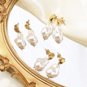 Close-up of three baroque pearl earrings with golden heart and shell textured studs