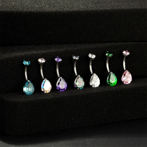 Détail macro de sept piercings de nombril en zircon goutte sur un présentoir noir