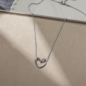 Elegant silver heart pendant necklace with minimalist snake chain design on display