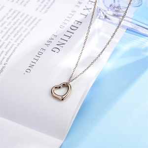 Collana con pendente a cuore traforato in oro rosa e zircone su sfondo di rivista bianca
