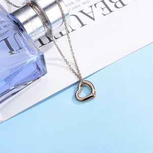 Collana in oro rosa con ciondolo a cuore traforato e zircone su sfondo blu chiaro