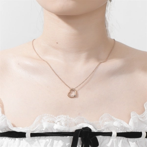 Collana in oro rosa con ciondolo a cuore traforato e diamante indossata da modella