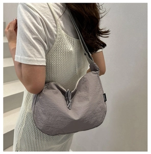 Detail of light purple nylon hobo bag featuring fabric texture and branded side label